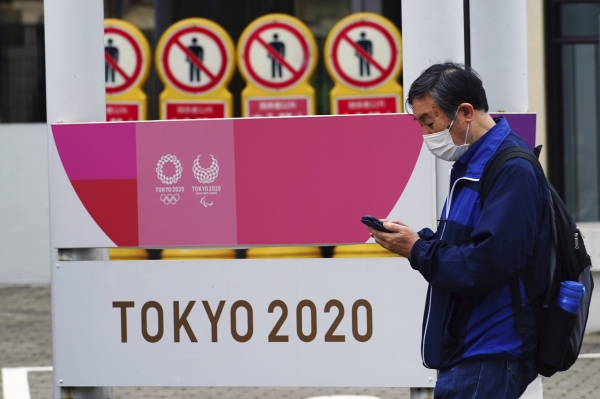 지난 5월 11일 일본 도쿄에서 코로나19 확산 방지를 위해 마스크를 쓴 한 남성이 2020 도쿄올림픽·장애인올림픽 홍보물 앞을 지나가고 있다.(도쿄=AP) ⓒ뉴시스